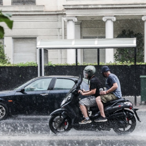 Αναβάτες σε μηχανάκια μούσκεμα από την καταρρακτώδη βροχή