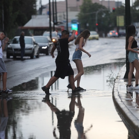 Πολίτες τρέχουν σε πλημμυρισμένο δρόμο υπό καταιγίδα
