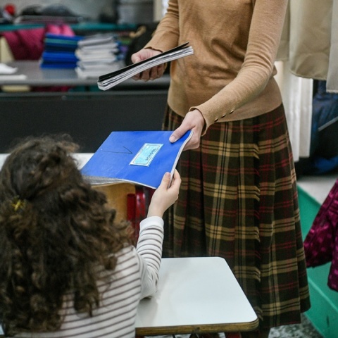 Μαθήτρια παίρνει το τετράδιο της από τη δασκάλα της σε αίθουσα δημοτικού σχολείου
