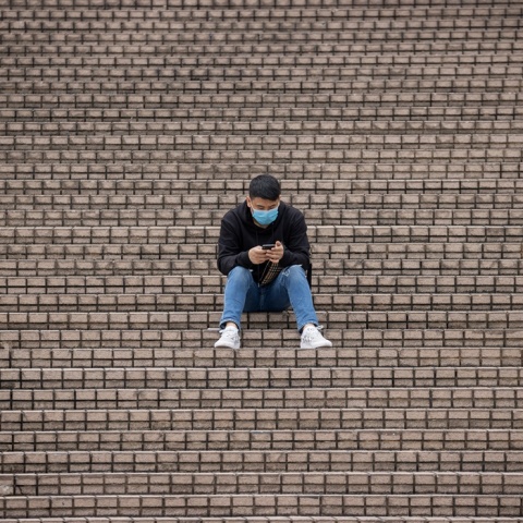 Πολίτης με μάσκα προστασίας από τον κορωνοϊό κάθεται σε σκαλιά