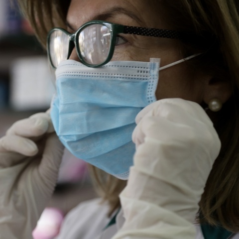 Γυναίκα με μάσκα και γάντια για την προστασία της από τη γρίπη