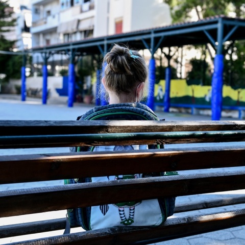 Παιδί με τη σχολική του τσάντα σε παγκάκι