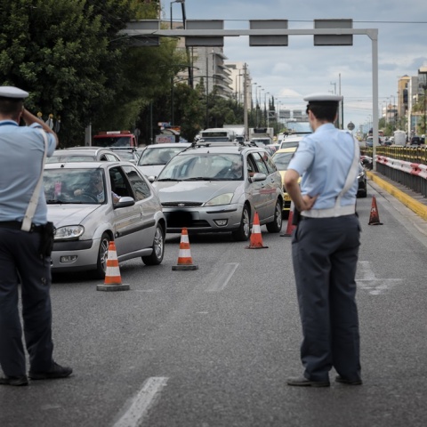 Τροχονόμοι διευθύνουν την κυκλοφορία των οχημάτων σε λεωφόρο όπου κώνοι έχουν αποκλείσει την αριστερή λωρίδα