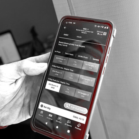 Χέρι που κρατάει κινητό τηλέφωνο με εφαρμογή στοιχημάτων