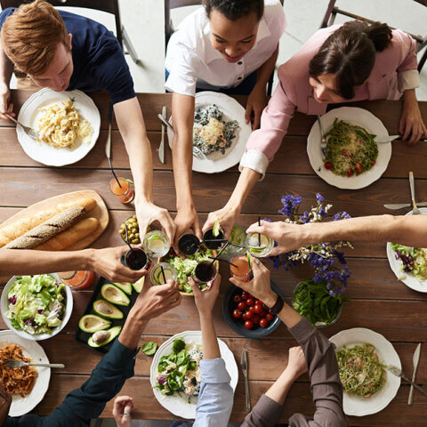 Παρέα τσουγκρίζει ποτήρια σε τραπέζι φαγητού