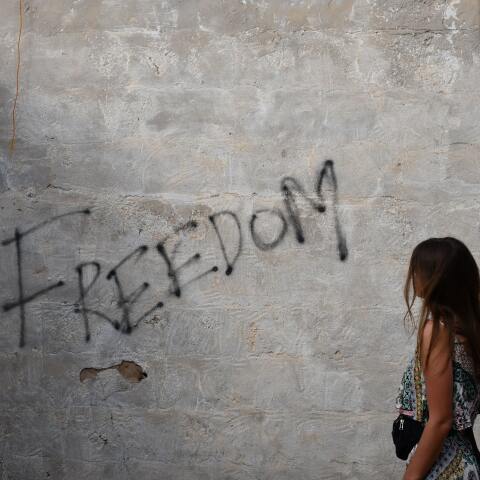 Κοπέλα κοιτάζει γκράφιτι σε τοίχο που γράφει «freedom»