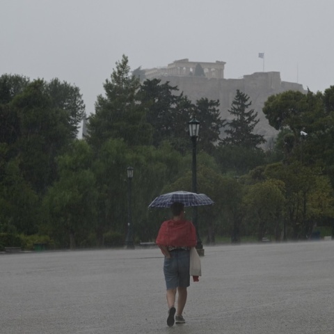 Άτομο σε δρόμο της Αθήνας κρατά ομπρέλα για να προστατευτεί από ισχυρή καταιγίδα