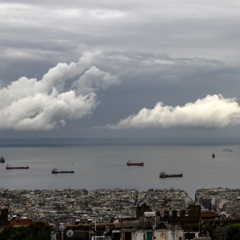 Συννεφιά σε σκοτεινό ουρανό λόγω της κακοκαιρίας πάνω από τη θάλασσα όπου πλέουν εμπορικά πλοία