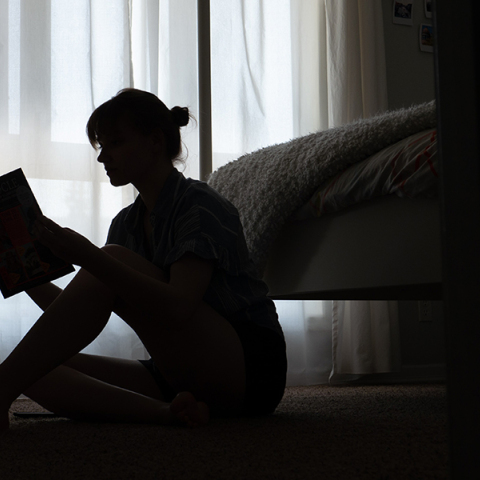 Κοπέλα καθισμένη στο πάτωμα διαβάζει βιβλίο