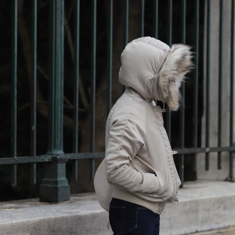 Γυναίκα προστατεύεται από το κρύο φορώντας μπουφάν και κουκούλα