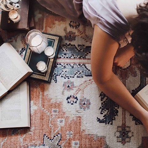 Άντρας ξαπλωμένος μπρούμυτα στο πάτωμα διαβάζει βιβλίο