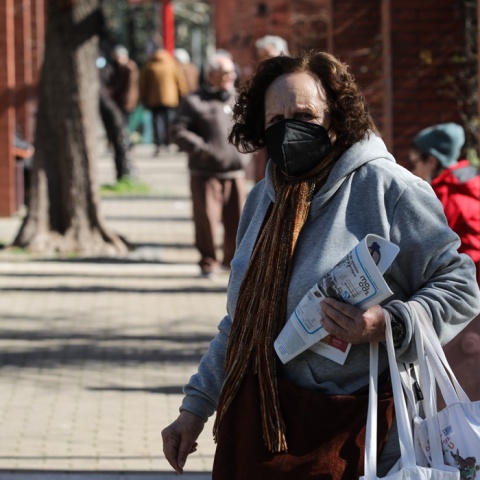 Ηλικιωμένη γυναίκα περπατά στον δρόμο κρατώντας περιοδικό