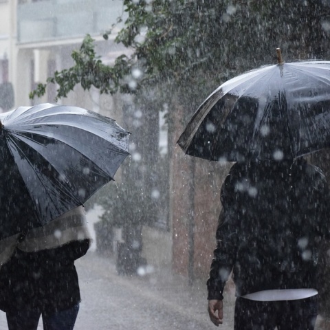 Πολίτες προστατεύονται με ομπρέλα από την ισχυρή βροχόπτωση