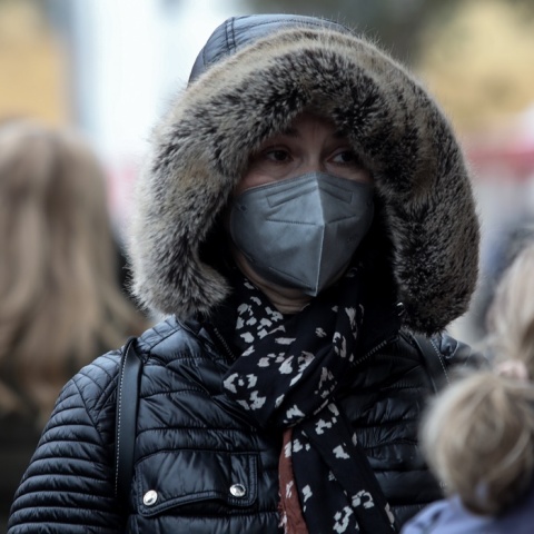 Γυναίκα με κουκούλα και κασκόλ προστατεύεται από το κρύο