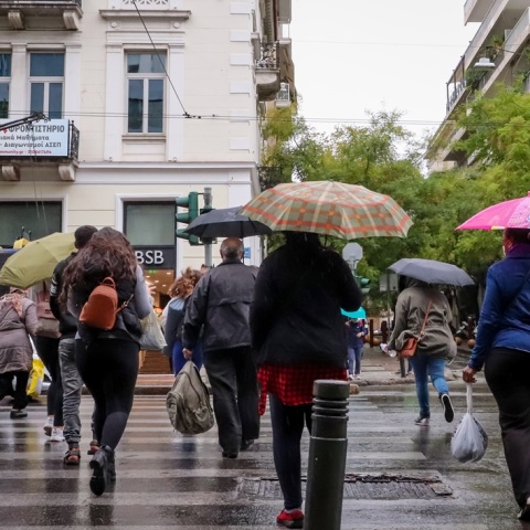 Πολίτες με ομπρέλα προστατεύονται από την καταιγίδα