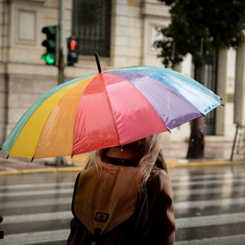 Γυναίκα κρατά ομπρέλα για να προστατευτεί από τη βροχή