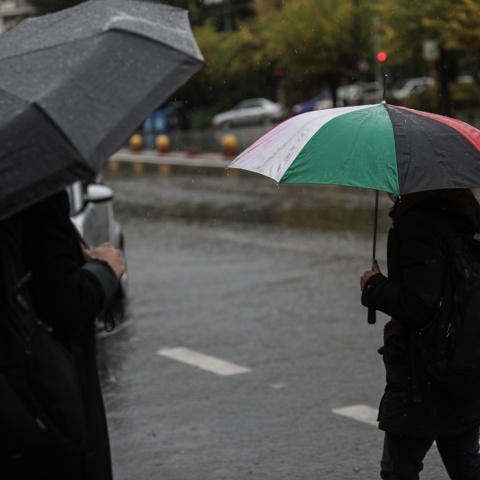 Άνδρας κρατά ομπρέλα περπατώντας στον δρόμο για να προστατευτεί από καταιγίδα