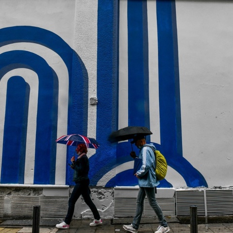 Πολίτες με ομπρέλα προστατεύονται από τη βροχόπτωση σε δρόμο της Αθήνας