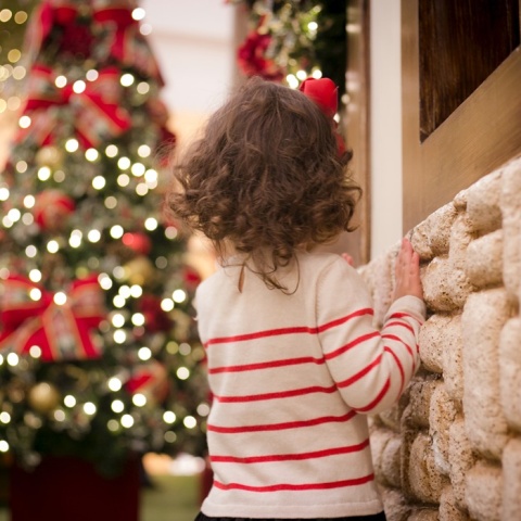 κοριτσάκι γυρισμένο σπίτι στην κάμερα με φόντο χριστουγεννιάτικο δέντρο