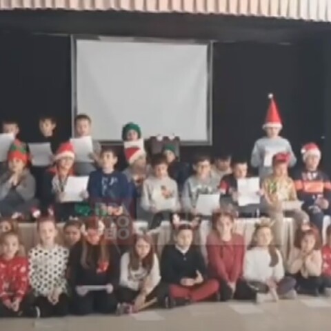 Μαθητές με χριστουγεννιάτικα καπέλα τραγουδούν το ένα δίπλα στο άλλο