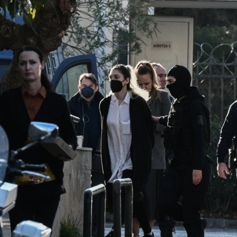 Η Ρούλα Πισπιρίγκου με λευκό πουκάμισο και μαύρο πανωφόρι οδηγείται στην ανακρίτρια