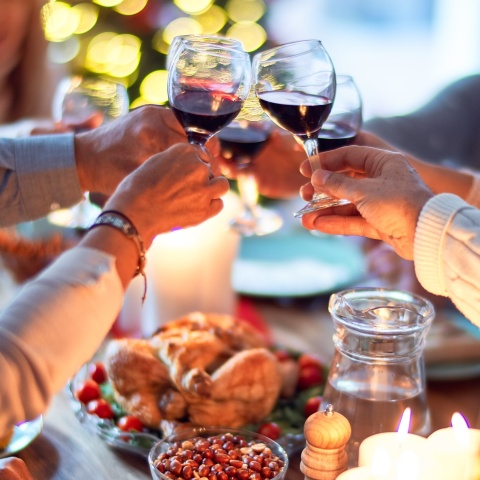 Άτομα τσουγκρίζουν τα ποτήρια με το κρασί τους στο χριστουγεννιάτικο τραπέζι