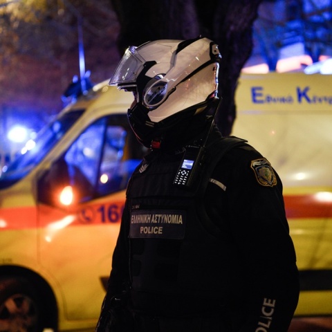 Αστυνομικός με κράνος μπροστά από ασθενοφόρο του ΕΚΑΒ