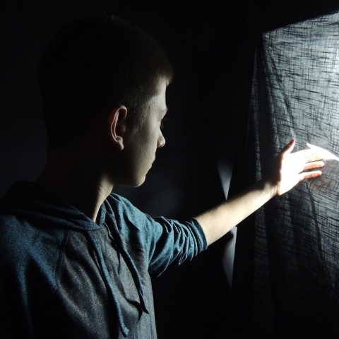 Αγόρι πίσω από κουρτίνα κοιτά μέσα από το κενό που υπάρχει
