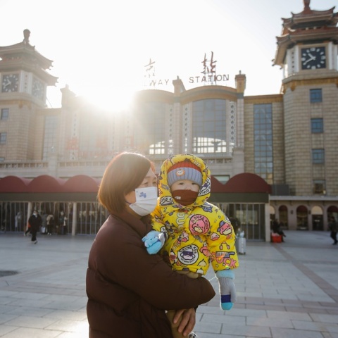 Γυναίκα με μωρό φορούν μάσκα προστασίας από τον κορωνοϊό σε πόλη της Κίνας