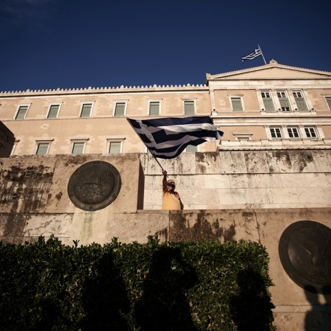 Άνδρας κυματίζει την ελληνική σημαία έξω από τη Βουλή των Ελλήνων