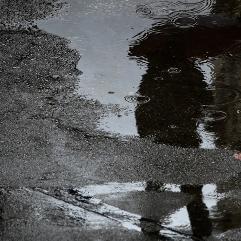 Η σκιά ατόμου με ομπρέλα σε λιμνάζοντα νερά