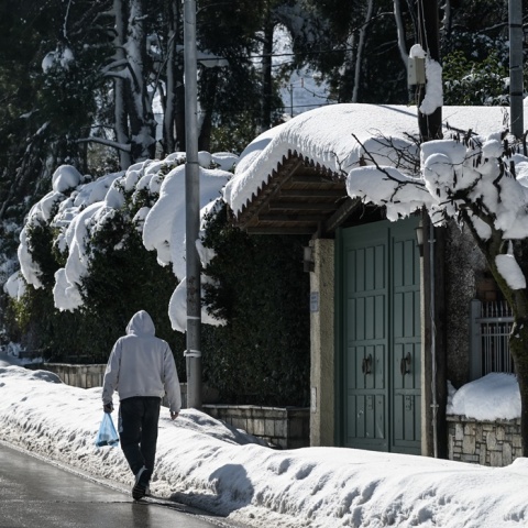 Άνδρας με σακούλα στο χέρι περπατά στον χιονισμένο Διόνυσο Αττικής