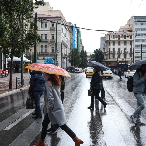 Πολίτες με ομπρέλα σε μία βροχερή μέρα στην καρδιά της Αθήνας