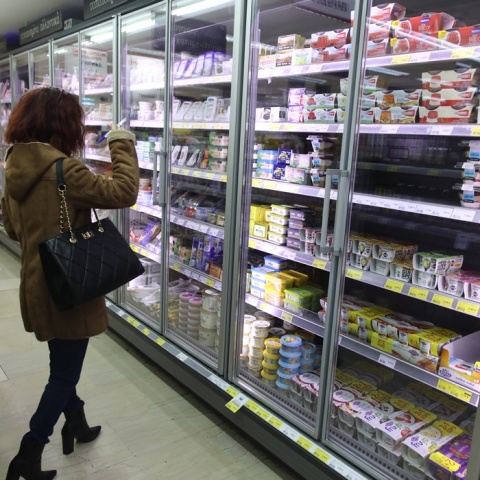 Γυναίκα μπροστά από ψυγείο σούπερ μάρκετ με γαλακτοκωμικά προϊόντα