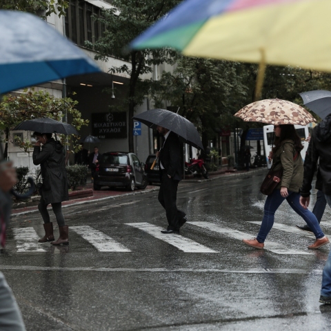 Πολίτες με ομπρέλες προστατεύονται από τη βροχή