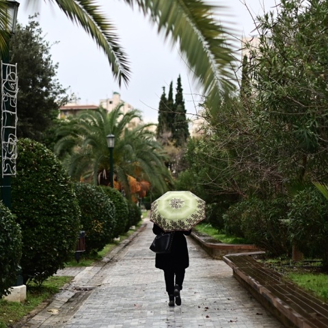 Γυναίκα με ομπρέλα περπατά στη βροχή