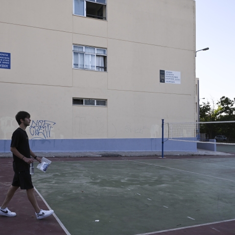 Μαθητής σε προαύλιο σχολείου με κάποια έγγραφα ανά χείρας