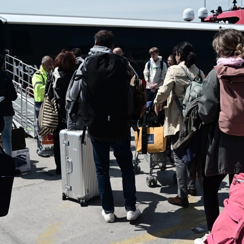 Επιβάτες με τις βαλίτσες ανά χείρας αναμένουν την επιβίβασή τους σε ταχύπλοο πλοίο στο λιμάνι του Πειραιά 