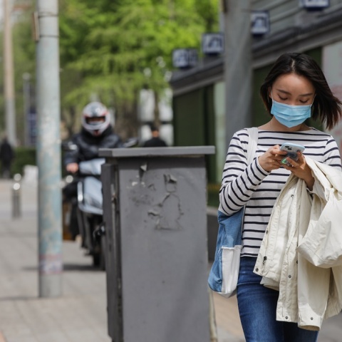 Γυναίκα με μάσκα προστασίας από τον κορωνοϊό περπατά σε δρόμο του Πεκίνου