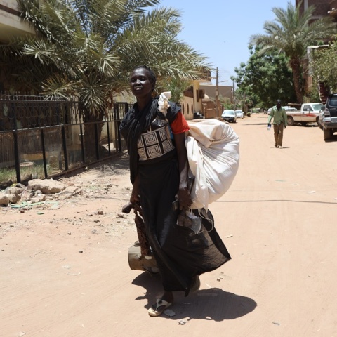 Γυναίκα έχει μαζέψει τα πράγματά της σε μπόγο και φεύγει από την περιοχή των μαχών