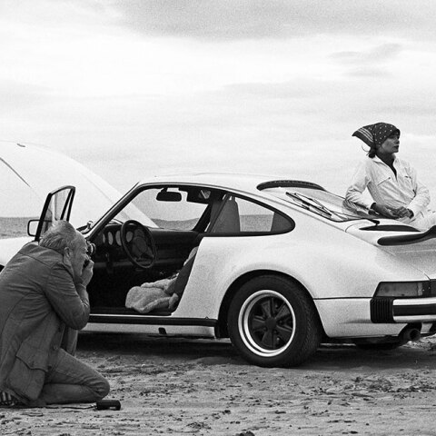 Ασπρόμαυρη φωτογραφία με γυναίκα που ποζάρει δίπλα σε Porsche