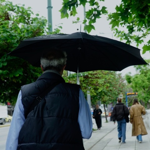 Άνδρας με ομπρέλα περπατά υπό βροχή