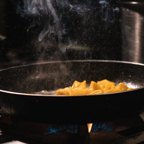 Τηγάνι πάνω στη φωτιά με φαγητό που μαγειρεύεται