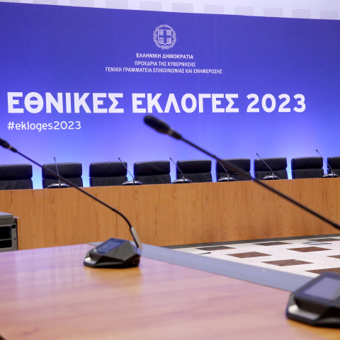 Στιγμιότυπο από το Κέντρο Τύπου στο Ζάππειο για τις εκλογές του 2023 - Δύο μικρόφωνα και πίσω οθόνη που γράφει «Εθνικές Εκλογές 2023» σε μπλε φόντο