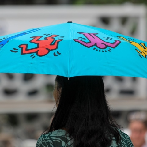 Γυναίκα με μπλε ομπρέλα προστατεύεται από τη βροχή