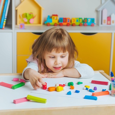 Παιδί παίζει με πλαστελίνες σε τραπεζάκι παιδικού σταθμού