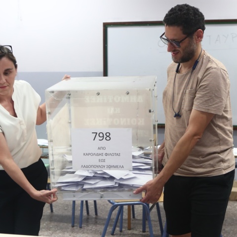 Δύο άτομα μεταφέρουν την κάλπη προκειμένου να την ανοίξουν και να καταγράψουν τις επιλογές των πολιτών