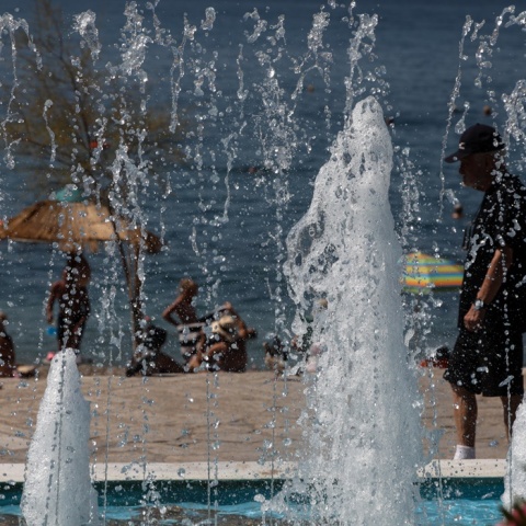 Άτομα σε παραλία διακρίνονται πίσω από σιντριβάνι στην περιοχή του Παλαιού Φαλήρου