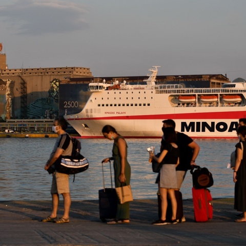 Επιβάτες με βαλίτσες ανά χείρας αναμένουν την επιβίβασή τους σε πλοίο