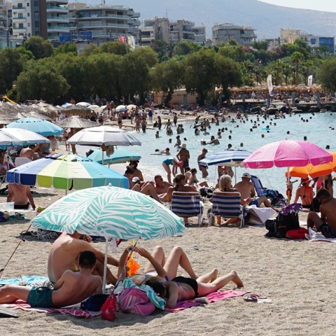 Λουόμενοι σε παραλία απολαμβάνουν ήλιο και θάλασσα